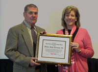 Philip Tennant accepts the REC award on behalf of his brother Walter J. Tennant Jr. from Board Chairwoman Kathleen A. Rapp.